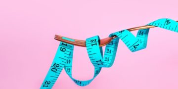 5fb29e063a37c Blue measuring tape and fork on pink background. Slim concept. Healthy lifestyle.