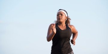 5ffc4f85ce04e A large woman jogging outside. The jogger wearing sports clothes, headband. Isolated on sky background image.