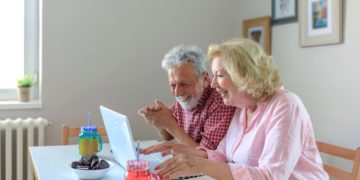 Happy senior couple surfing the internet with laptop computer.Senior couple using together laptop at home.
