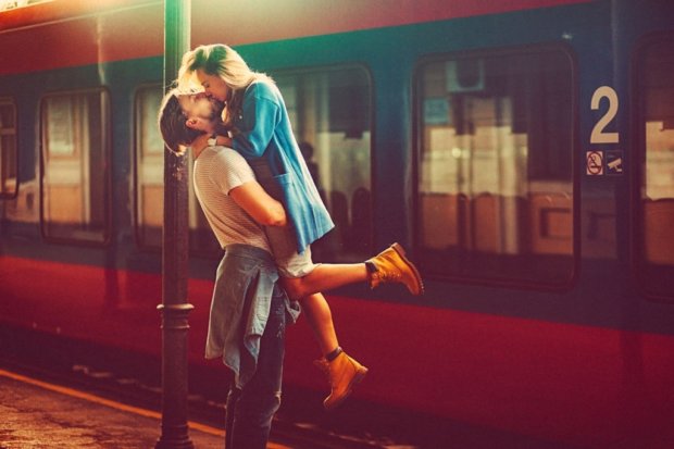 Passionate young man and woman kissing beside the train at the railway station. The shot is executed with available natural light, and the copy space has been left.