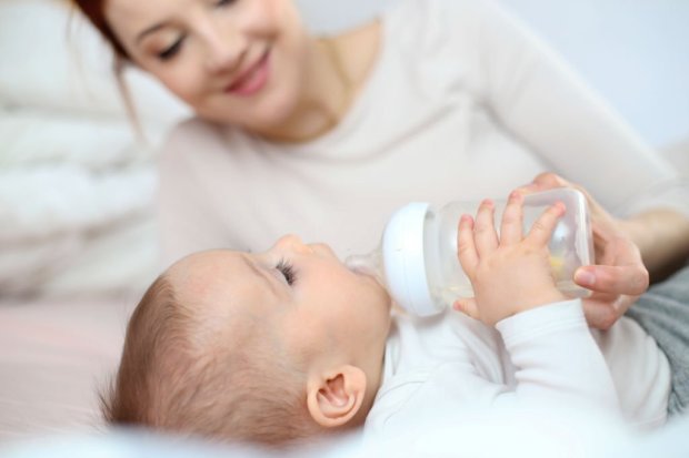 Single mid adult Caucasian mother and her baby at home, baby drinking from a baby bottle.