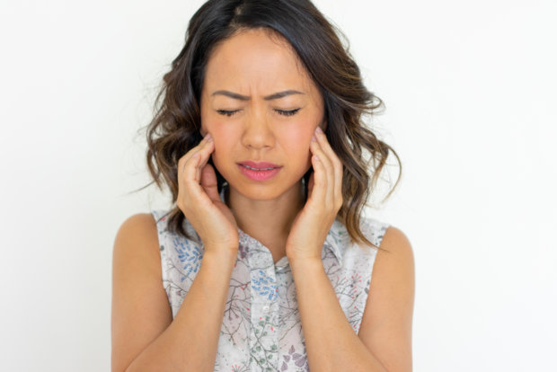 Worried young woman frowning and touching cheeks. Pretty Asian lady having toothache. Dental care concept. Isolated front view on white background.