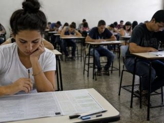 Candidatos realizam prova de concurso público em uma sala de aula.